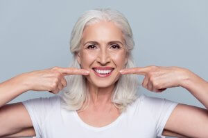 smiling mature woman points at teeth